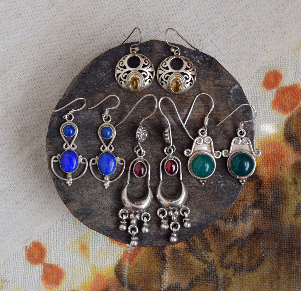 Set of silver earrings with gemstones on a textured surface