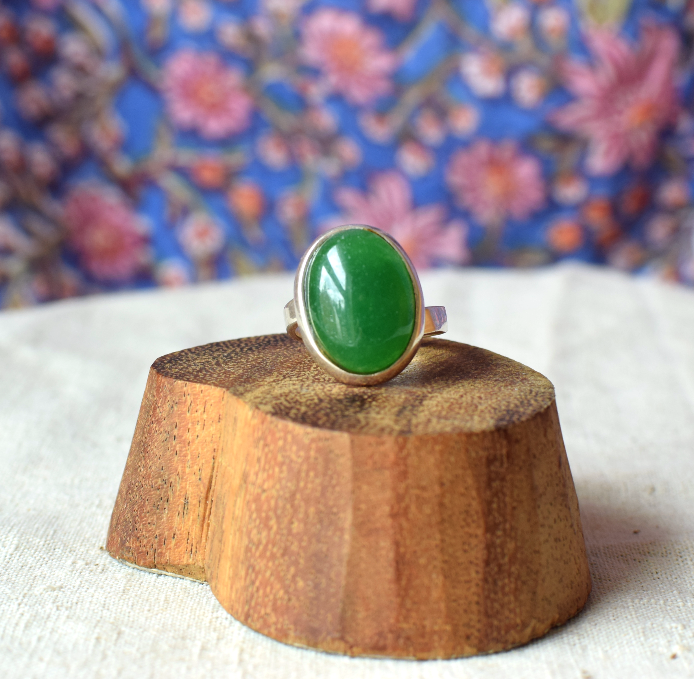 Green ring on a wooden stand with a floral background