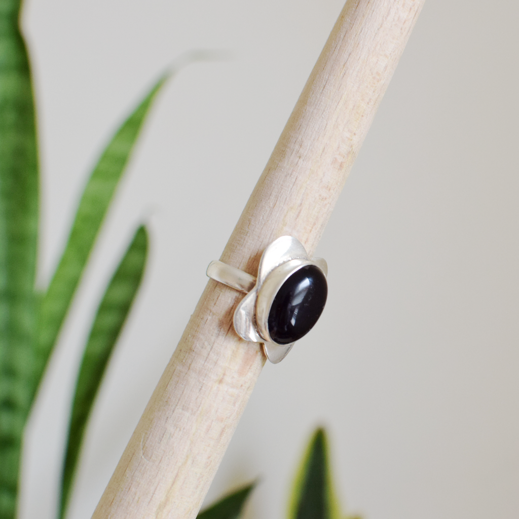 Silver ring with a black stone on a branch with a natural background