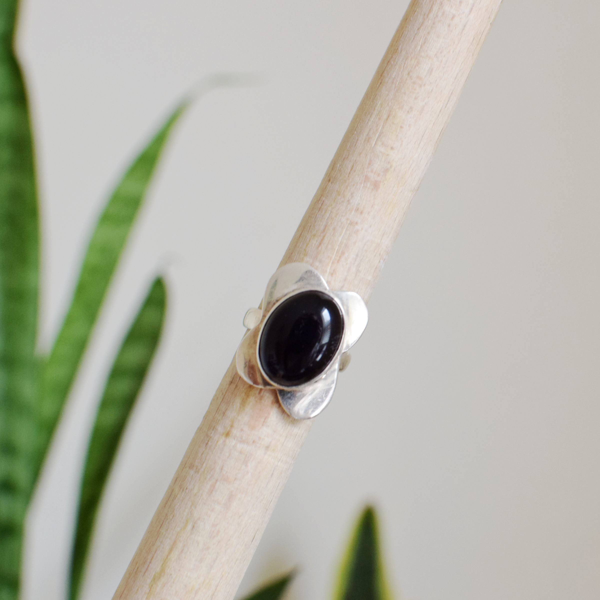 Silver ring with a black stone on a wooden stick with a natural background